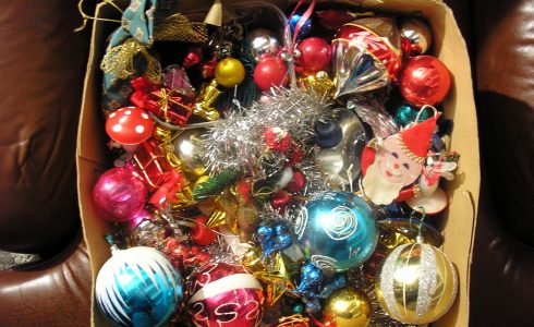Box of Christmas ornaments on leather furniture.