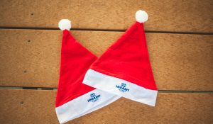 HHHunt Homes branded Santa hats on wooden table.