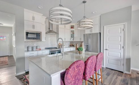 Bright model kitchen with quartz counter tops and white cabinets.