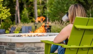 woman drinking coffee sitting outdoors looking at firepit