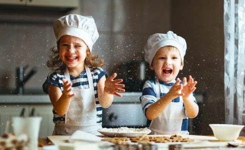 two children cooking in kitchen in chefs hats