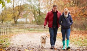 Man, woman and dog walking on trail in fall