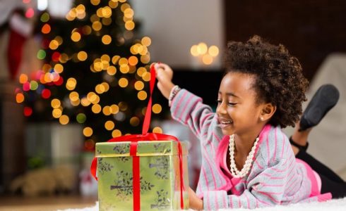 child opening gift by Christmas tree