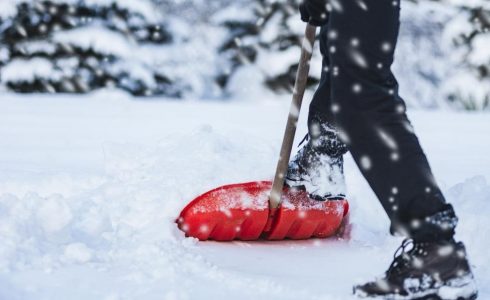 person shoveling snow with red shovel