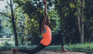 woman in orange top doing yoga outdoors spring summer exercise