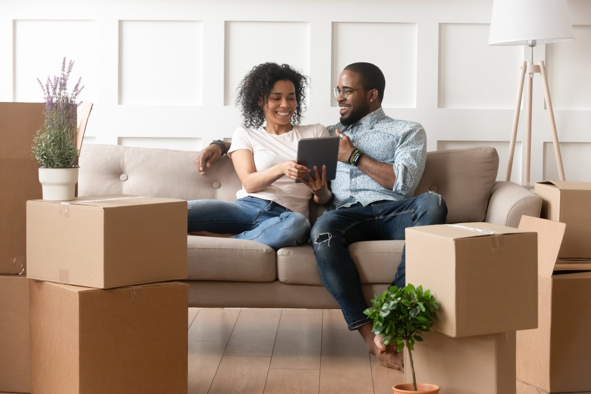 Smiling couple use digital tablet on moving day